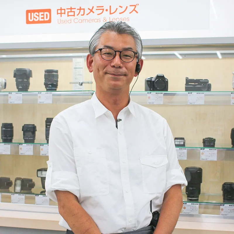 カメラのキタムラ 中古カメラ・レンズ売り場に立つスタッフ